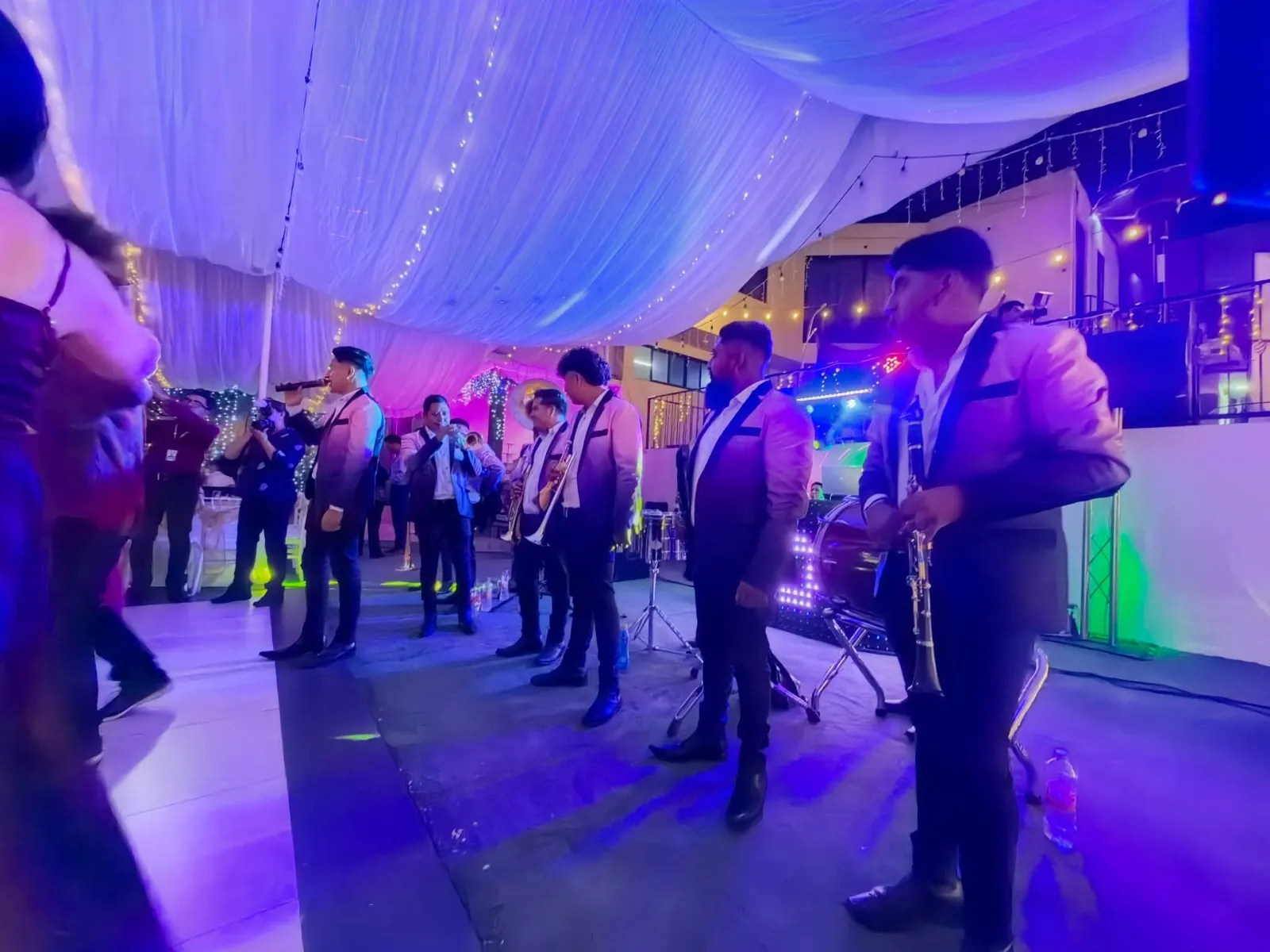 Banda sinaloense en vivo durante una fiesta con iluminación violeta